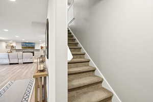 Staircase with wood finished floors and recessed lighting