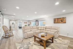 Living room with a barn door, recessed lighting, and light wood-type flooring