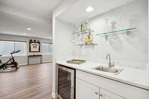 Indoor wet bar with wine cooler, light wood finished floors, and recessed lighting