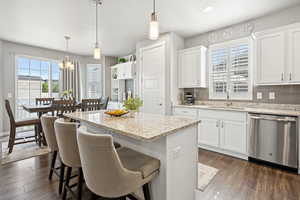 Kitchen featuring dishwasher, a kitchen island, white cabinets, tasteful backsplash, and recessed lighting