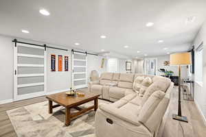 Living area featuring a barn door, recessed lighting, and light wood-style flooring