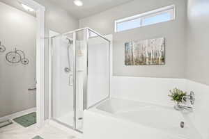 Full bath featuring a garden tub, a stall shower, and marble look tile flooring