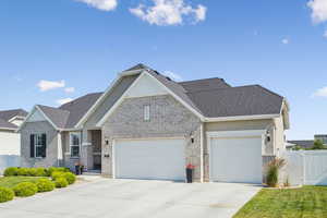 View of front of property featuring an attached garage, concrete driveway, brick siding, and a shingled roof