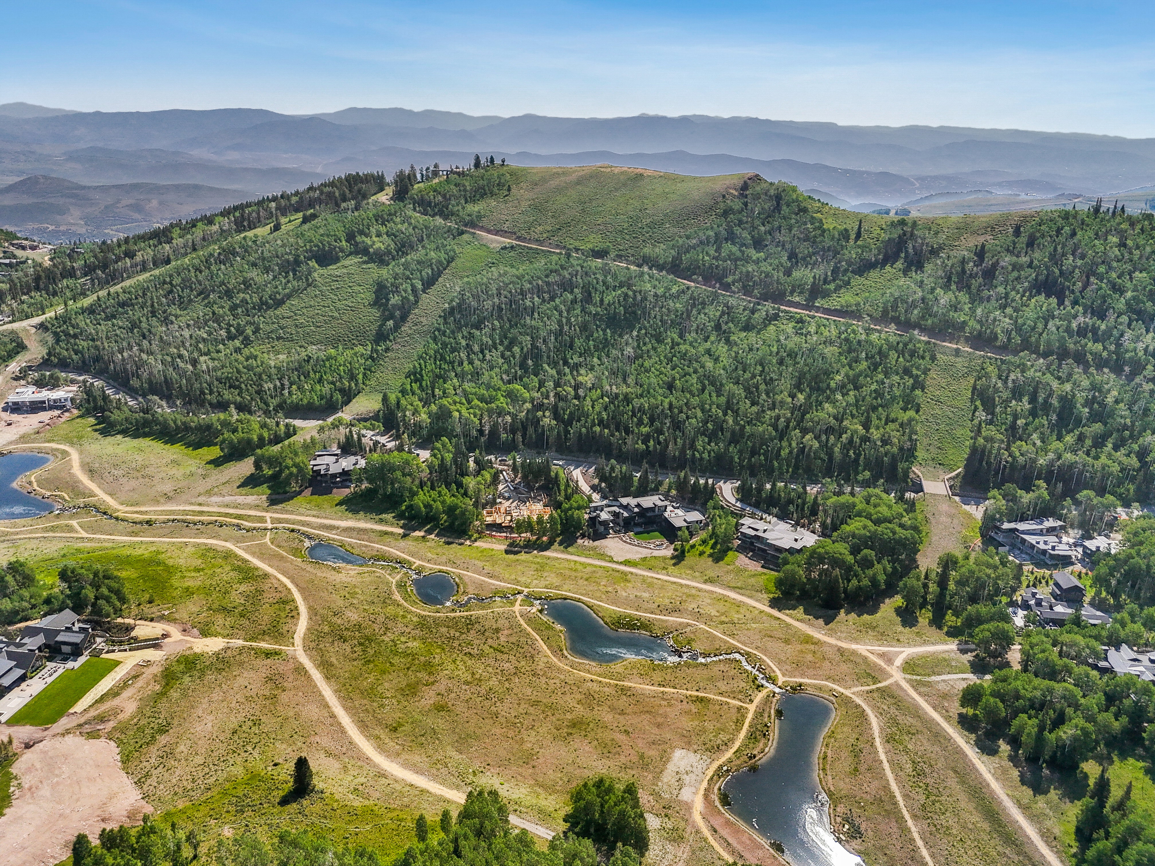 Aerial overview of property's location with a water and mountain view and a forest