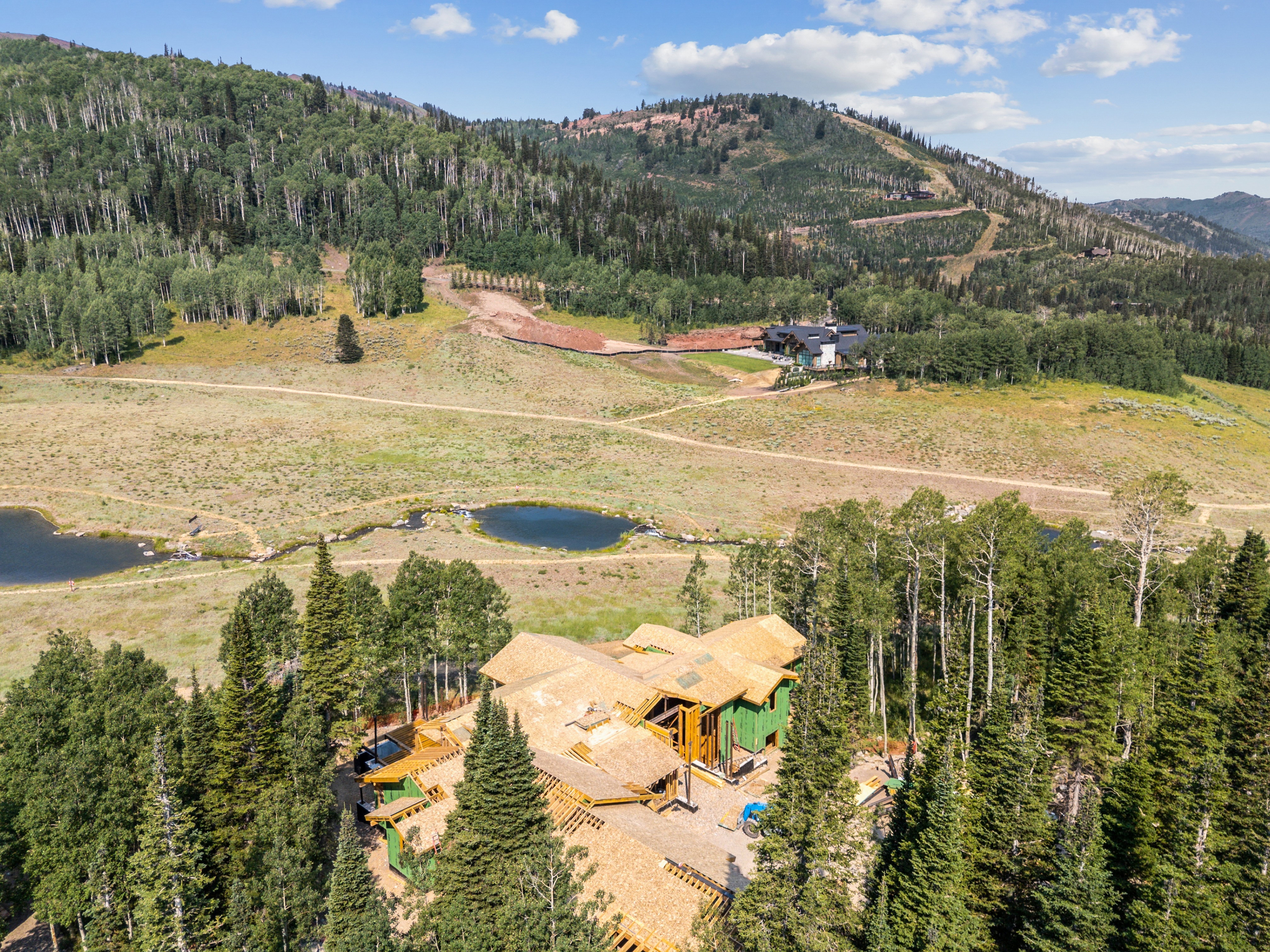 Newly constructed residence featuring a multi-level roofline, extensive decking, and a wooded setting