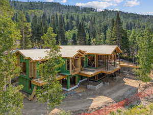 Back of house with a wooded view, a shingled roof, and a deck