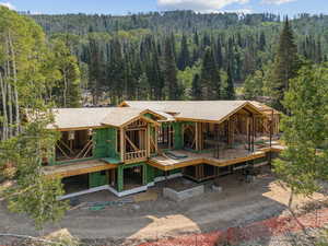 Back of house with a view of trees and a shingled roof