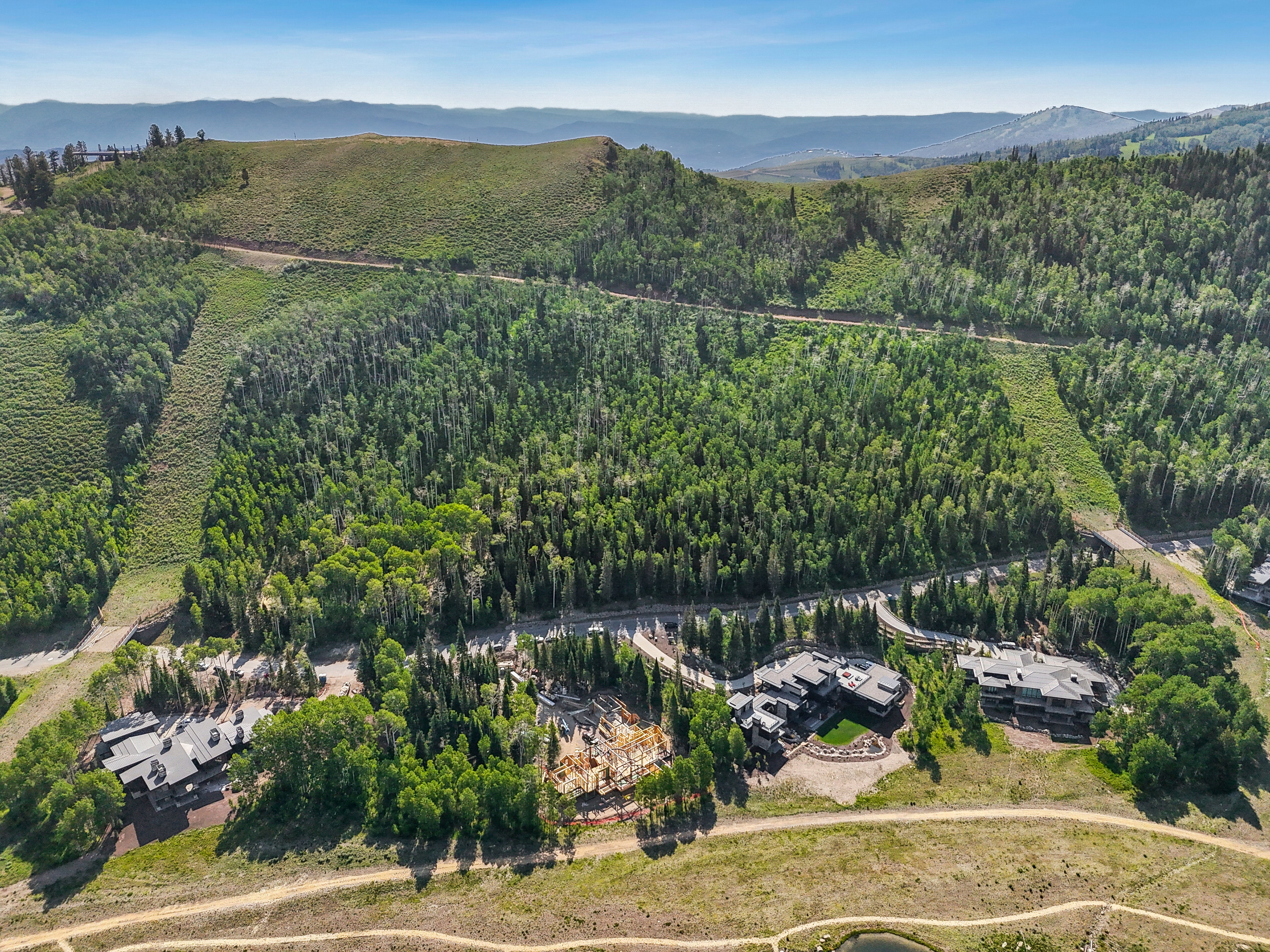 Aerial view of property and surrounding area featuring a heavily wooded area and a mountainous background