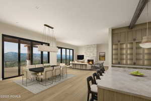 Dining space featuring a mountain view, a stone fireplace, light wood-type flooring, and beam ceiling