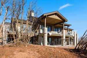 Back of house featuring a balcony, a chimney, and a patio area