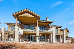 Back of property with a chimney, a balcony, and a patio area