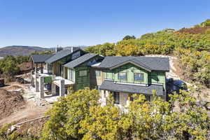 View of side of property featuring roof with shingles, stone siding, and a patio