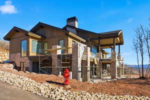 View of property exterior with a balcony, a chimney, a patio area, and stone siding