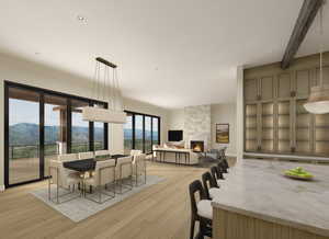Dining room with a mountain view, a stone fireplace, light wood-type flooring, and beam ceiling