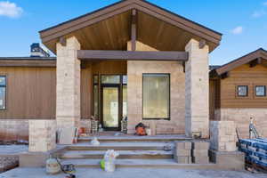 Property entrance featuring stone siding and covered porch