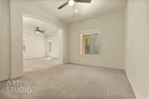 Spare room featuring ceiling fan, carpet floors, and arched walkways