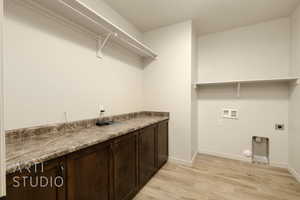 Washroom with hookup for an electric dryer, light wood finished floors, hookup for a washing machine, cabinet space, and hookup for a gas dryer