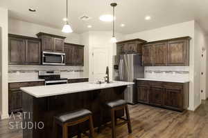 Kitchen with appliances with stainless steel finishes, tasteful backsplash, light countertops, dark wood-style flooring, and recessed lighting