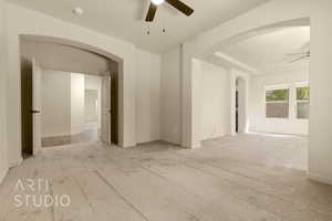 Spare room with ceiling fan, arched walkways, and carpet