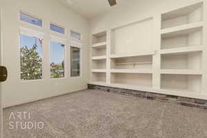 Empty room featuring carpet flooring, built in features, and ceiling fan