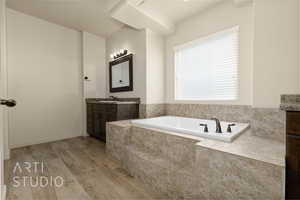 Full bathroom with vanity, a garden tub, and wood finished floors