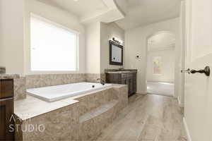Bathroom featuring vanity, a garden tub, and wood finished floors