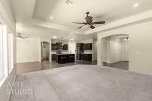 Unfurnished living room featuring arched walkways, ceiling fan, carpet flooring, and recessed lighting