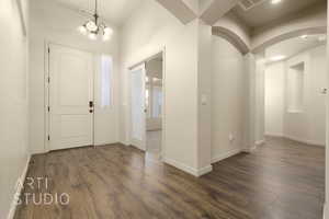 Foyer featuring dark wood finished floors, arched walkways, and a chandelier