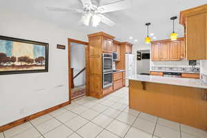 Kitchen with stainless steel appliances, a peninsula, light stone counters, a ceiling fan, and recessed lighting