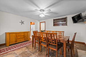 Dining space featuring ceiling fan and dark stone finish floors