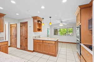 Kitchen featuring appliances with stainless steel finishes, light tile patterned floors, open shelves, ceiling fan, and a peninsula