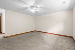 Carpeted spare room featuring a ceiling fan and baseboards
