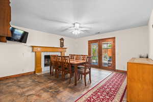 Dining room featuring a ceiling fan, french doors, and a tiled fireplace