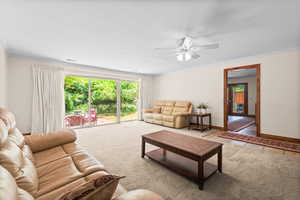 Living room with ornamental molding, ceiling fan, carpet floors, and tile patterned floors