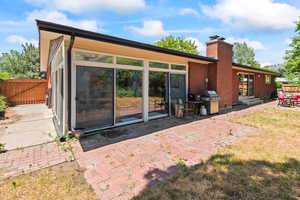 Rear view of house featuring a chimney, a patio, and a gate