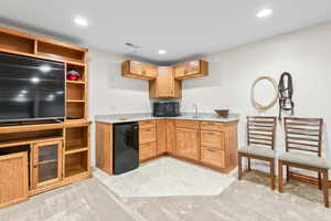 Kitchen with fridge, black microwave, light countertops, recessed lighting, and open shelves