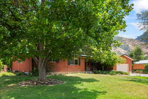Obstructed view of property with brick siding, an attached garage, and a front lawn