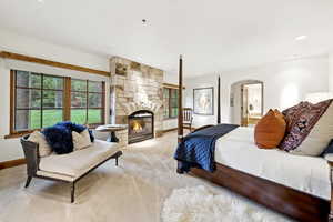 Carpeted bedroom with arched walkways, multiple windows, a fireplace, recessed lighting, and connected bathroom
