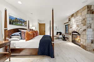 Carpeted bedroom featuring a stone fireplace