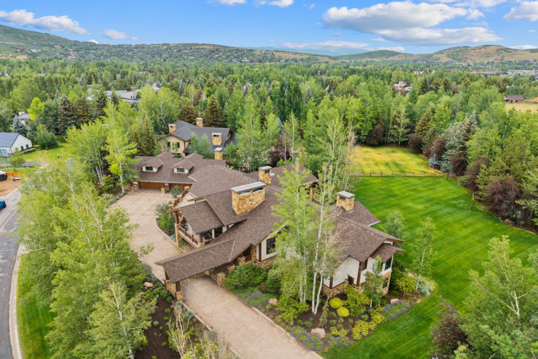 Aerial view of property and surrounding area with a heavily wooded area and a mountainous background