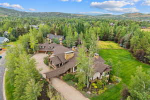 Aerial view of property and surrounding area with a heavily wooded area and a mountainous background