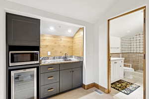 Bar area with wine cooler, stainless steel microwave, and lofted ceiling