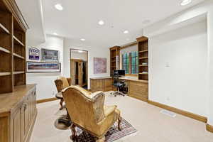 Office featuring light colored carpet, built in study area, and recessed lighting