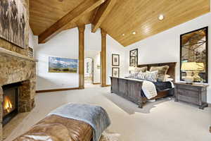 Carpeted bedroom with wooden ceiling and a stone fireplace