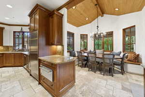 Kitchen featuring stone tile floors, a warming drawer, stainless steel refrigerator, recessed lighting, and light stone countertops