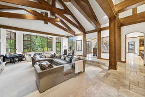 Living area with arched walkways, stone tile floors, beam ceiling, and high vaulted ceiling