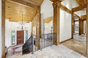 Entryway with a chandelier, wooden ceiling, stone tile flooring, and high vaulted ceiling