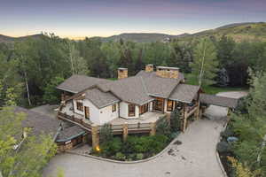 View of front of home with concrete driveway, a chimney, stucco siding, a view of trees, and a mountain view