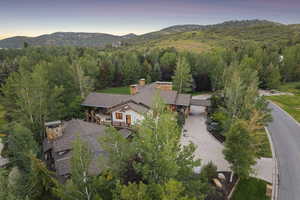 Aerial view of property's location featuring a mountain backdrop and a heavily wooded area