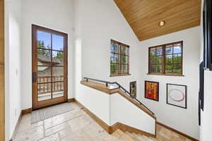 Entrance foyer with high vaulted ceiling, stone tile flooring, and wooden ceiling